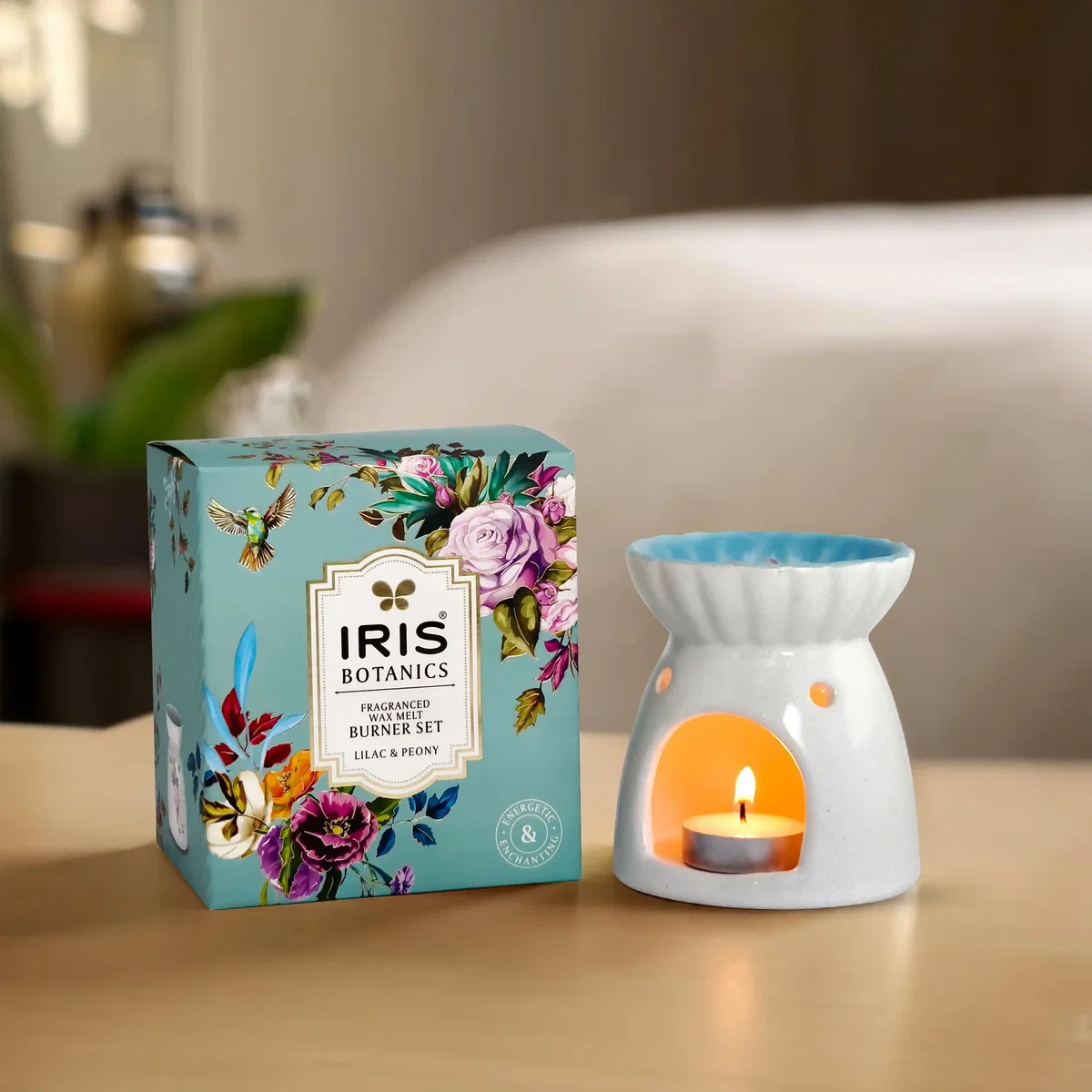Lit ceramic soy wax burner with tealight beside its packaging