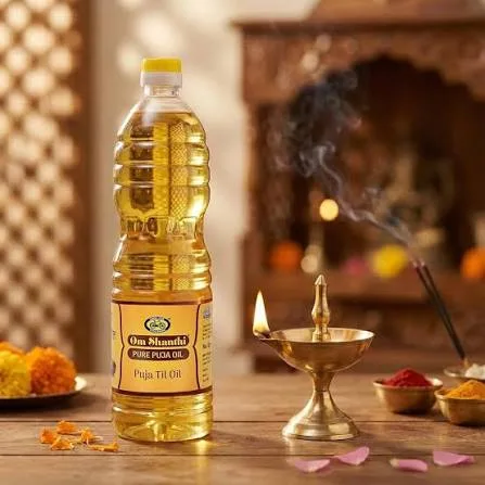 Puja oil bottle beside a lit brass lamp with marigolds
